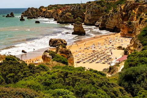 Algarve beach with golden cliffs and green vegetation